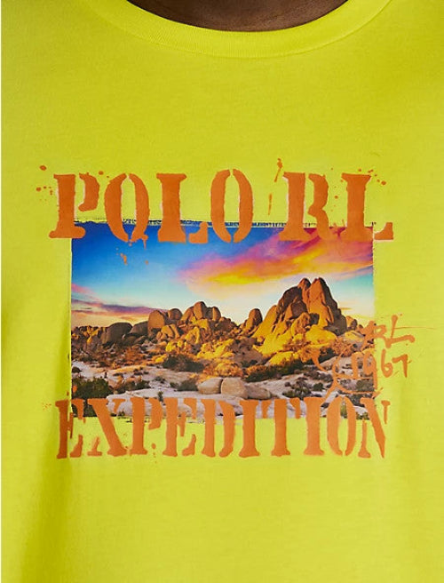 Translation missing: en.A close-up of a bright neon yellow Polo Ralph Lauren t-shirt featuring a graphic print of a desert landscape with orange text reading 'POLO RL EXPEDITION'